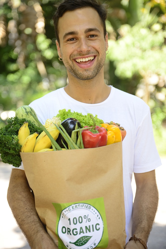 Happy man carrying a bag full of organic food.